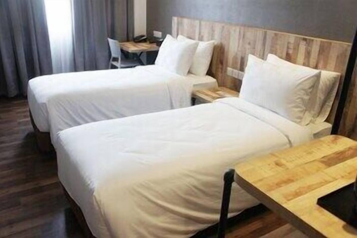 Une chambre d’hôtel avec deux lits, une tête de lit en bois, un bureau et une chaise.