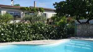 A swimming pool surrounded by lush greenery and a house with a tiled roof. - Studio meublé de vacances, very quiet in nature and culture ancient and modern (Sanilhac-Sagriès)