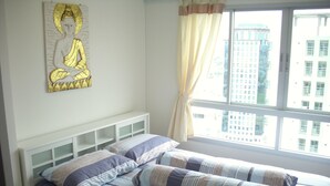 Un dormitorio con cama, ventana con cortinas y un adorno en la pared.