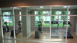 Un gimnasio con equipo de ejercicio, ventanas amplias y vistas al exterior.