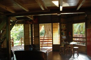 A wooden cabin interior with a dining area, bookshelves, and a view of the outdoors. - My cabin-Star Trail (POINTE NOIRE)