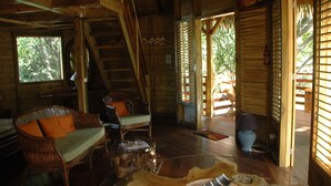 A wooden cabin interior with a staircase, wicker furniture, and a glass coffee table. - My cabin-Star Trail (POINTE NOIRE)