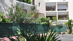 A modern apartment building with balconies, a green fence, and various plants. - Ermitage Les Bains - Apt F2 - Ground floor - Lagoon proximity (SAINT GILLES LES BAINS)