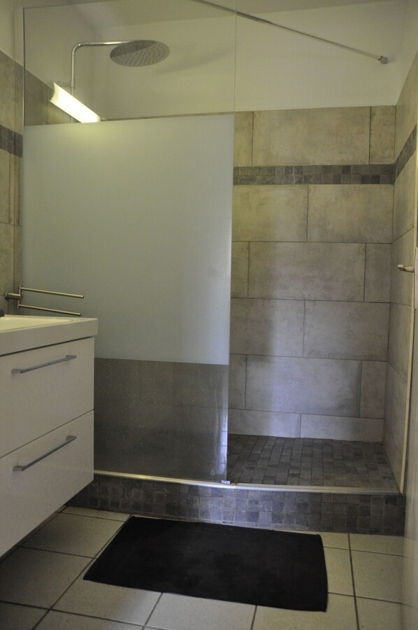 Un baño moderno con ducha, lavabo y espejo.
