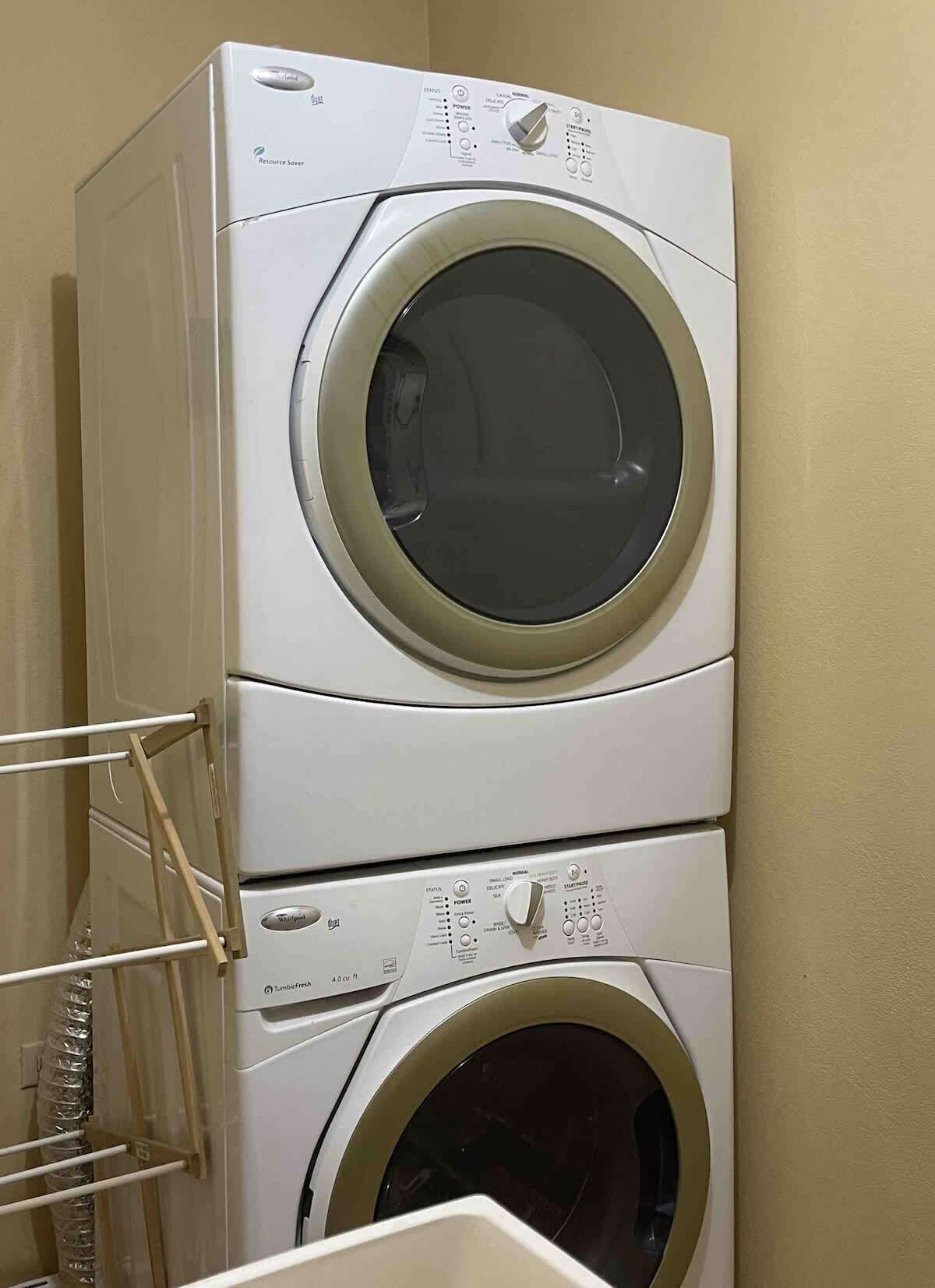 A stacked washer and dryer unit with control panels and a hose reel.