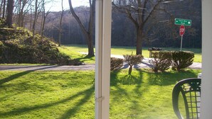 A view from a porch with a stop sign, a green directional sign, and a grassy area with trees. - GRANDMAS VACATION HOME ON REEDS  CREEK, WV No WiFi or cell service. No hottub!! (Franklin)