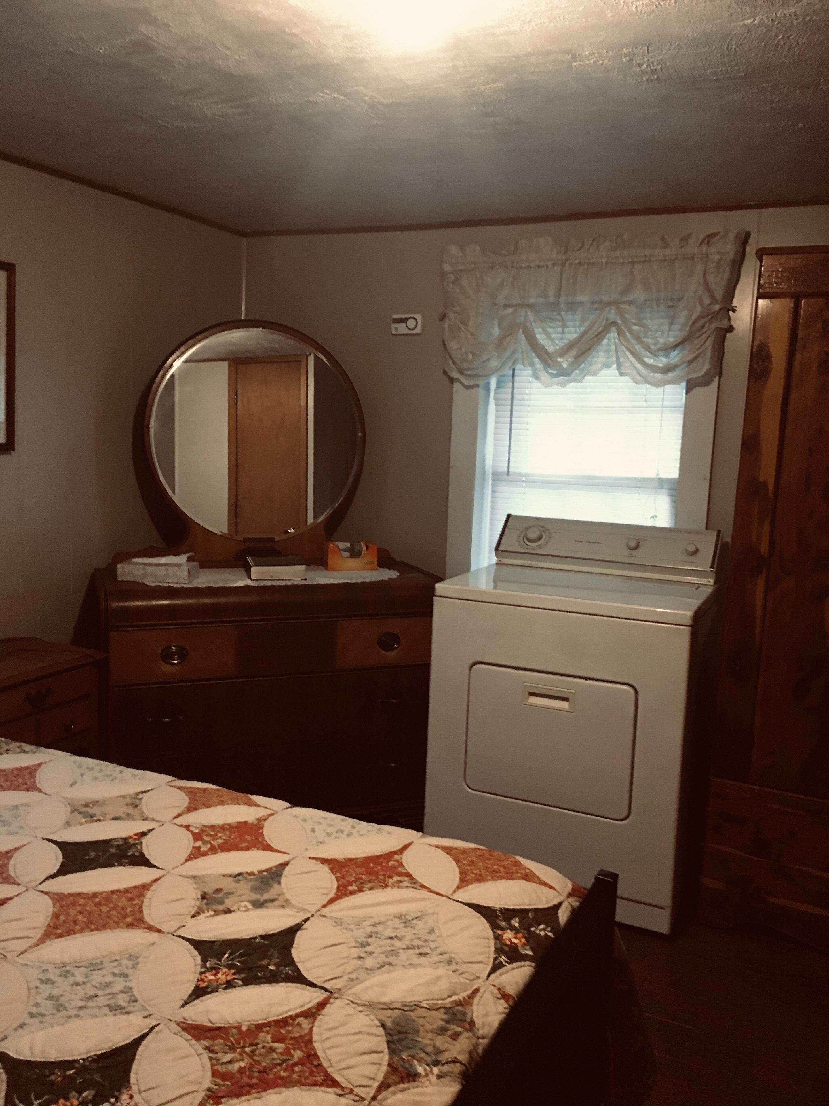 Un dormitorio con cama, cómoda, espejo, ventana y lavadora.