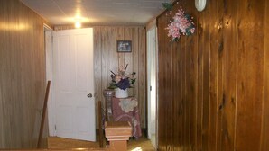 A wooden hallway with a closed door, a small table with a vase of flowers, and a wooden bench. - GRANDMAS VACATION HOME ON REEDS  CREEK, WV No WiFi or cell service. No hottub!! (Franklin)