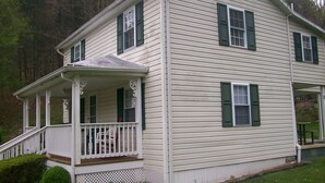 A two-story house with a porch, green shutters, and a small front yard. - GRANDMAS VACATION HOME ON REEDS  CREEK, WV No WiFi or cell service. No hottub!! (Franklin)