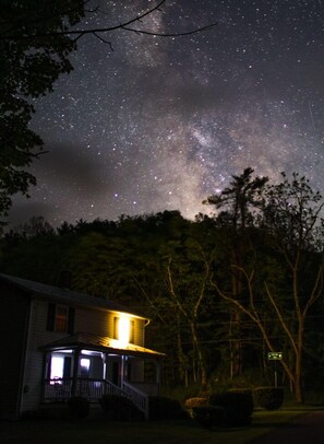 A house with a porch under a starry night sky. - GRANDMAS VACATION HOME ON REEDS  CREEK, WV WITH WIFI. (Franklin)