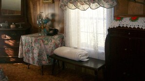 A room with wooden walls, a floral tablecloth-covered table, a bench with a white towel, a vintage telephone, and a picture frame on the wall. - GRANDMAS VACATION HOME ON REEDS  CREEK, WV No WiFi or cell service. No hottub!! (Franklin)
