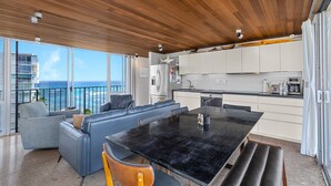 A modern kitchen with white cabinets, a black countertop, and a wooden ceiling. - True Top Floor Penthouse Residence with 360 Degree Views & A/C (Honolulu)