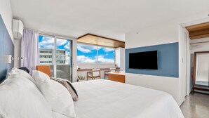 A modern hotel room with a large bed, a desk, a flat-screen TV, and a view of the sky through a large window. - True Top Floor Penthouse Residence with 360 Degree Views & A/C (Honolulu)