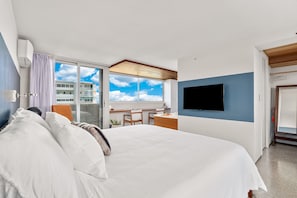 A modern hotel room with a large bed, a desk, a flat-screen TV, and a view of the sky through a large window. - True Top Floor Penthouse Residence with 360 Degree Views & A/C (Honolulu)
