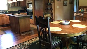 Una cocina con armarios de madera, una isla central, una mesa de comedor con individuales y una alfombra estampada.