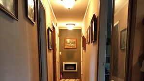 Un pasillo con suelo de madera, cuadros en las paredes, una chimenea y una alfombra.