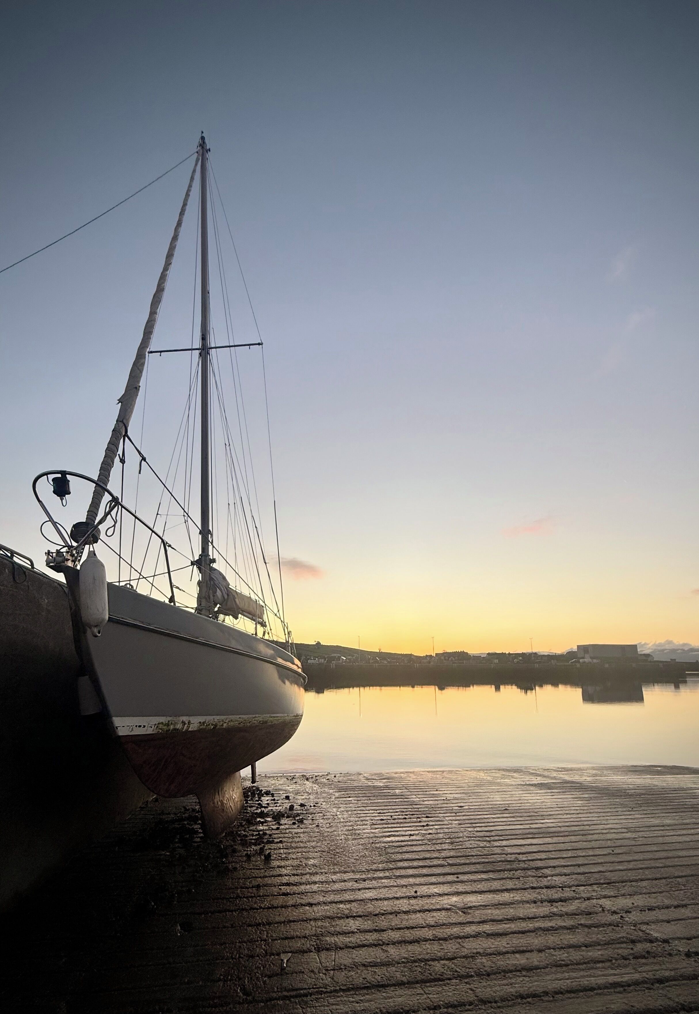 Un barco amarrado en un muelle con un cuerpo de agua tranquilo que refleja el cielo.