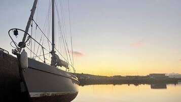 Un barco amarrado en un muelle con un cuerpo de agua tranquilo que refleja el cielo.