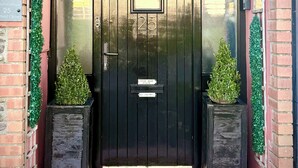 A black door with the number 25, flanked by two potted plants, and a sign indicating 'No Junk Mail'. - Harriet's Cottage. Chic & Cozy, Walk Everywhere! (Dingle)