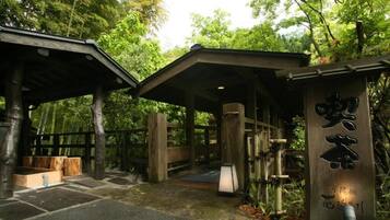 A traditional Japanese wooden structure with a covered entrance and a stone pathway leading to it.