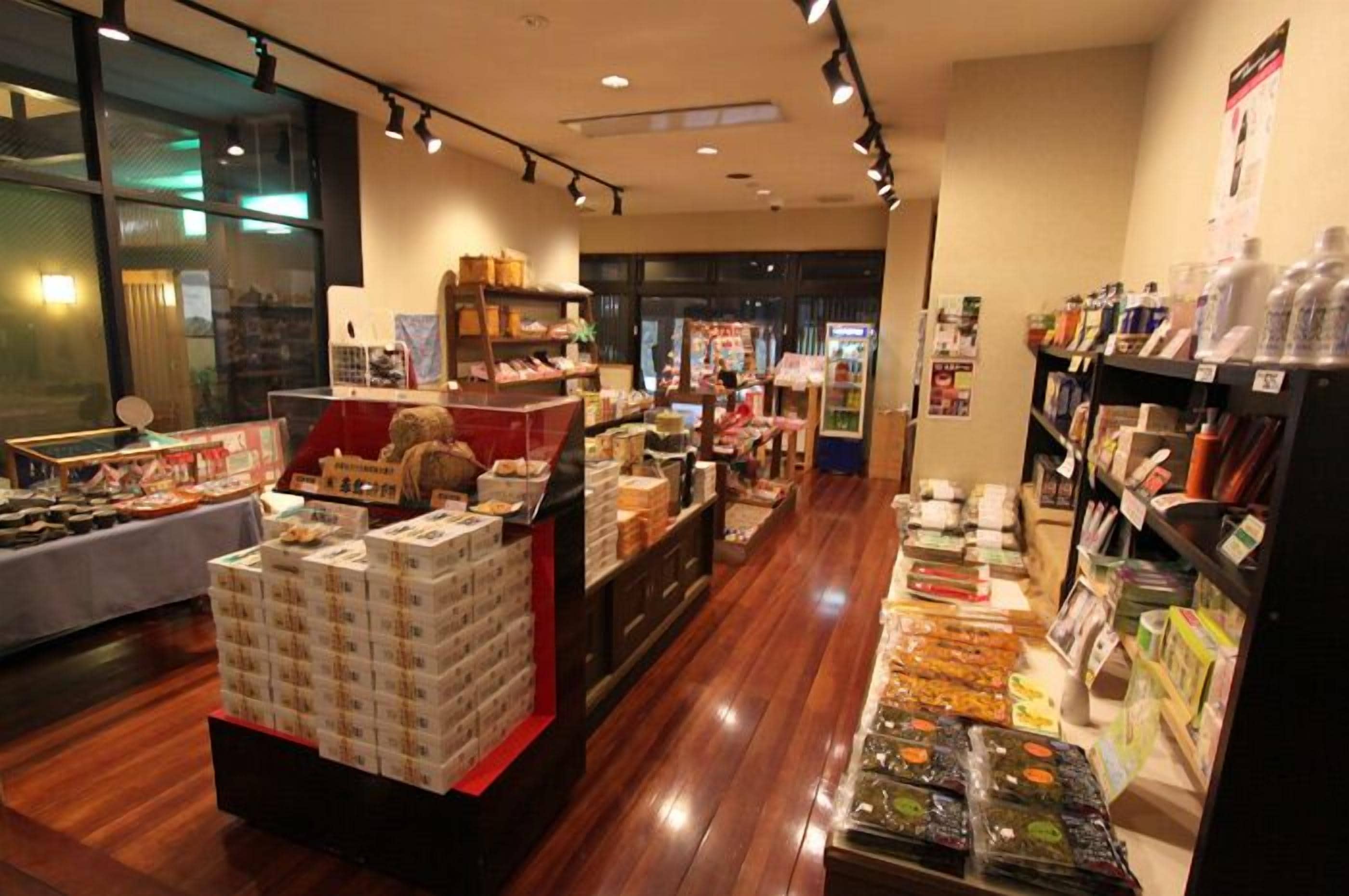 A well-lit store with wooden flooring, shelves stocked with various products, and a display counter with boxes.