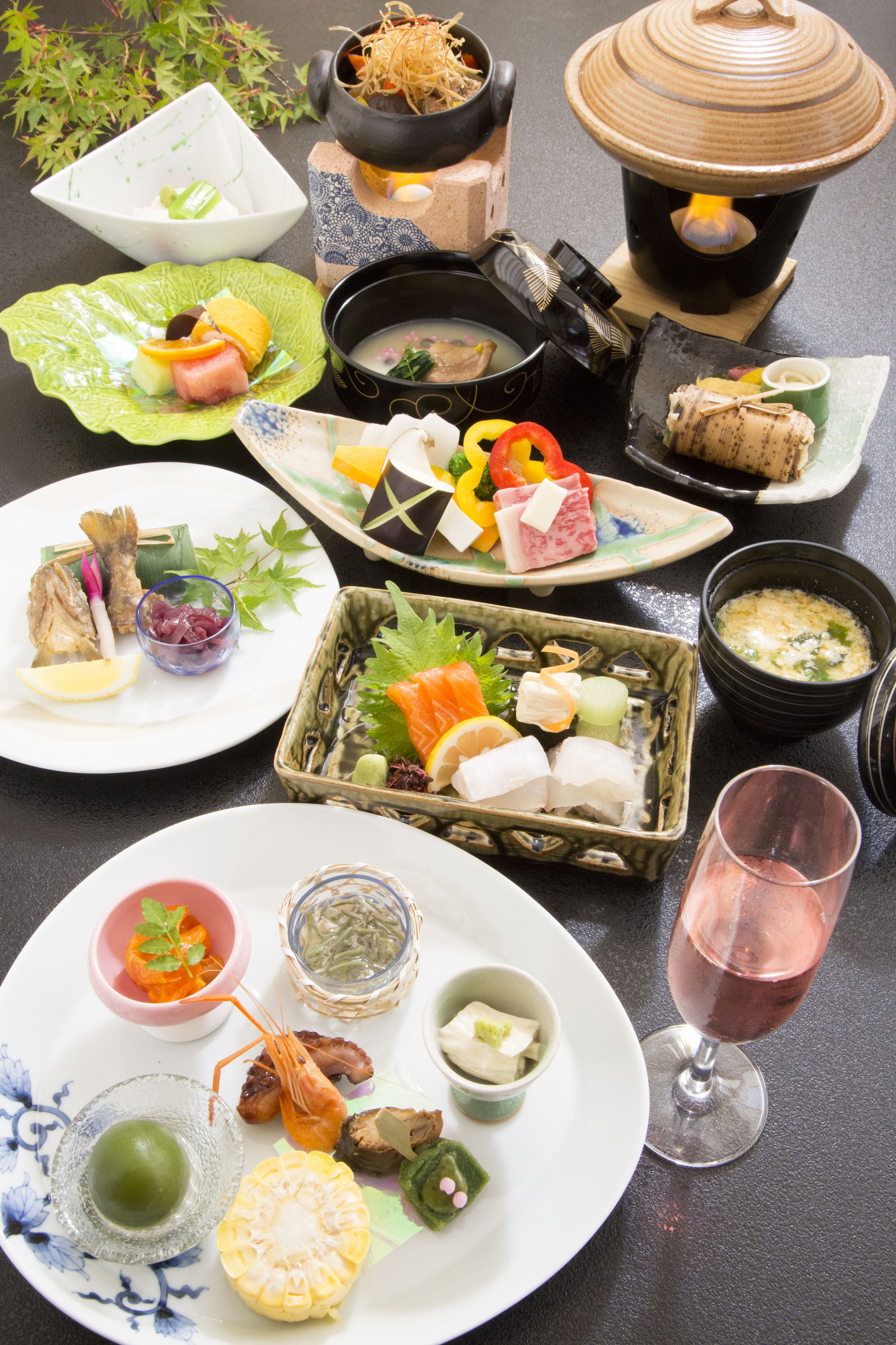 Variedad de platos japoneses sobre una mesa, incluyendo sushi, sashimi y una olla caliente.