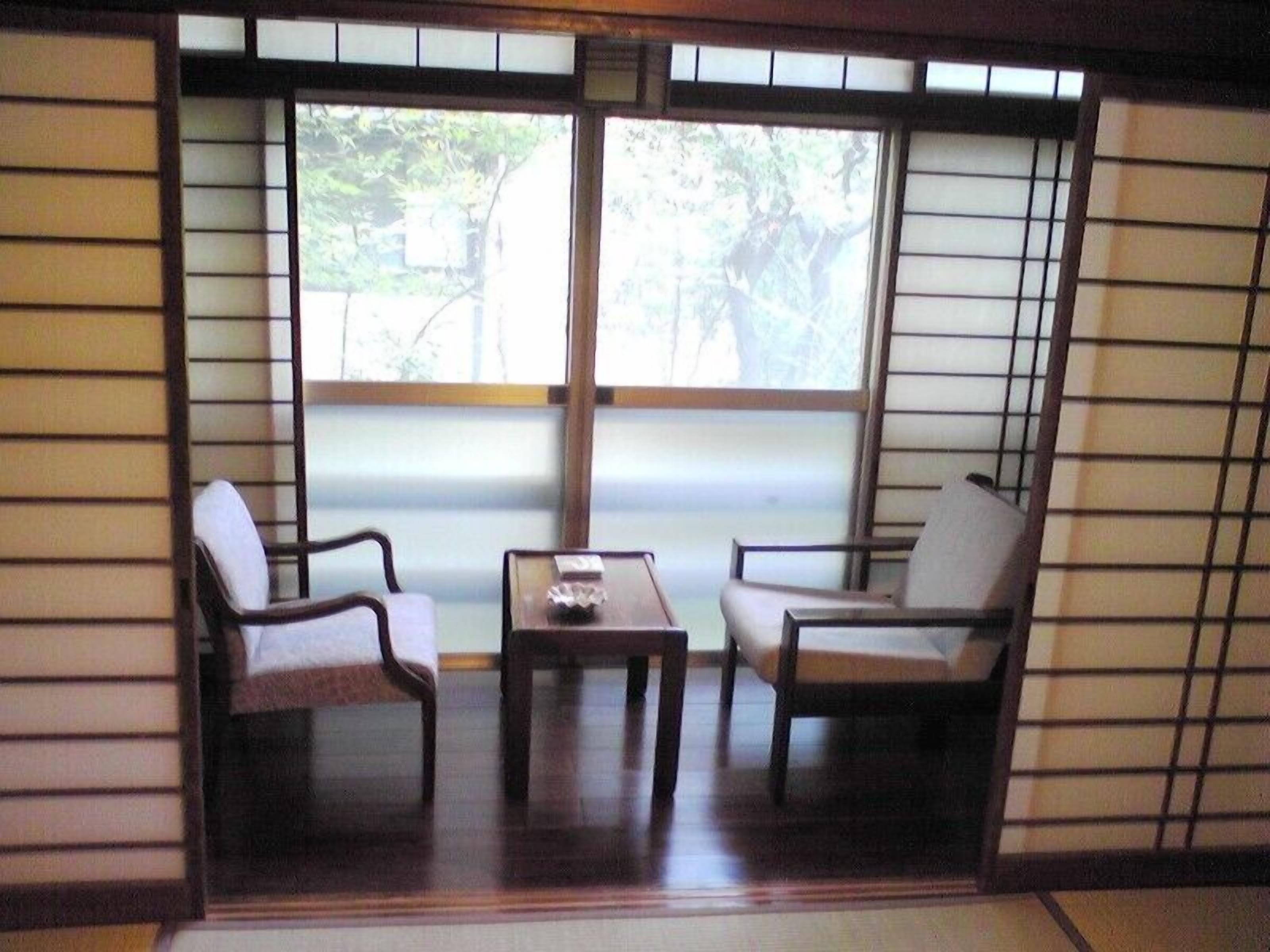Una habitación japonesa tradicional con suelo de tatami, una mesa baja y dos sillas.