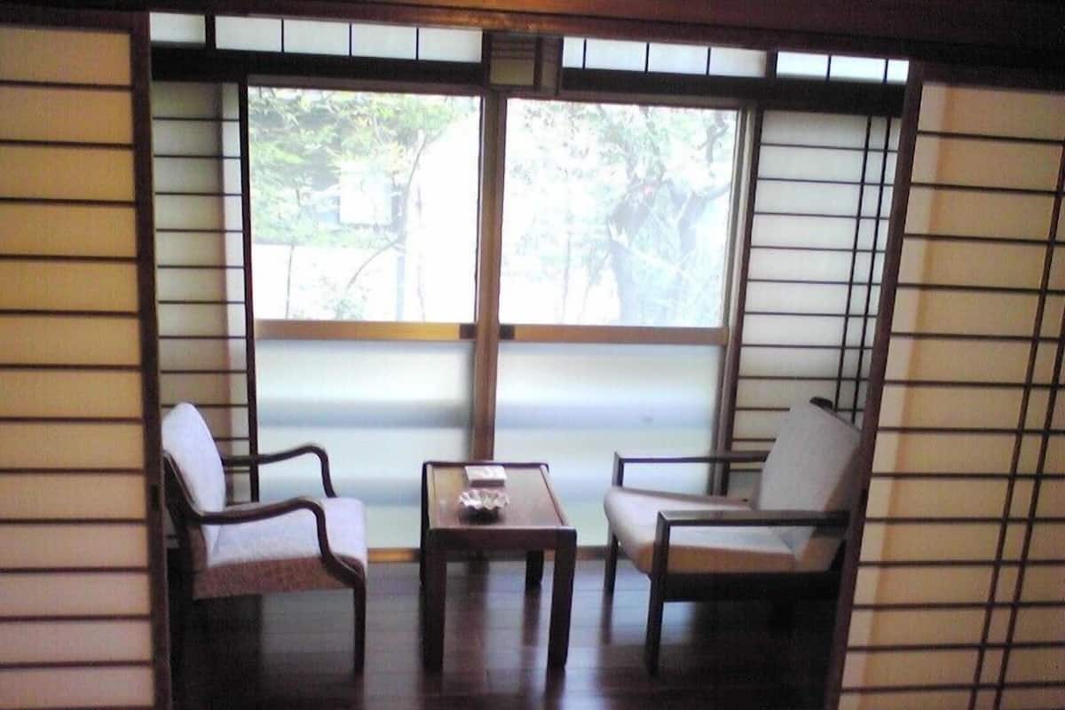 A traditional Japanese room with tatami flooring, a low table, and two chairs.