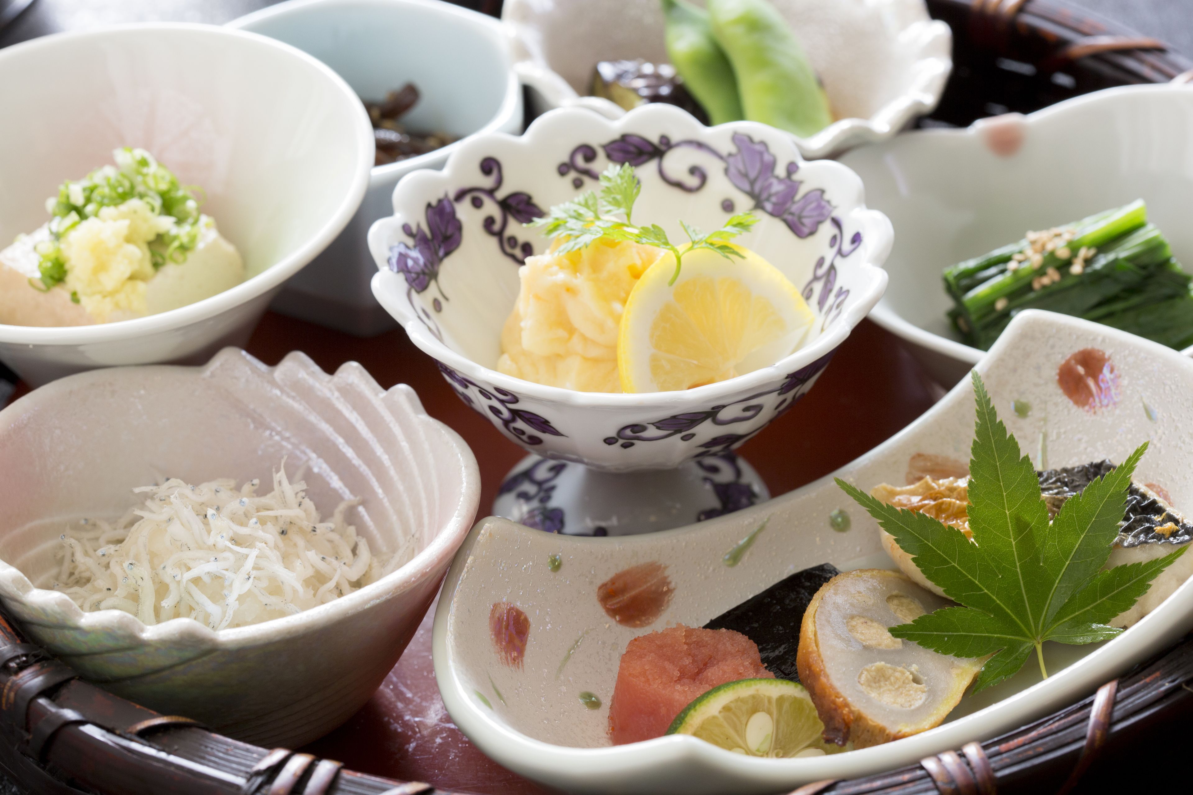 A variety of dishes in traditional bowls, including a bowl with a decorative leaf garnish.