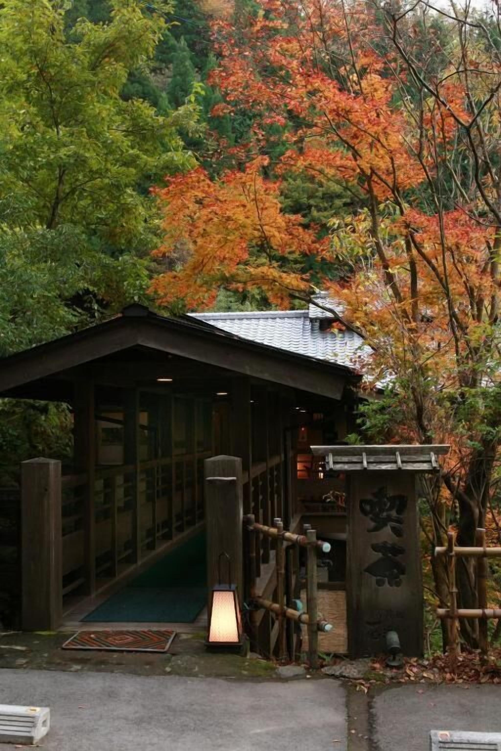 A traditional Japanese building with a wooden structure, a covered walkway, and a sign with Japanese characters.