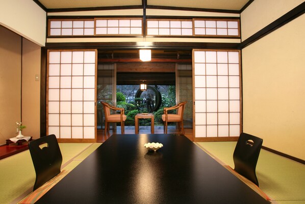 A traditional Japanese room with tatami flooring, a black table with a decorative bowl, and two wooden chairs. - Kurokawa Onsen Yumerindo (Minamioguni)