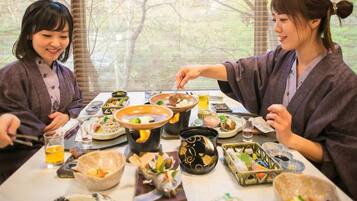 A dining table with various dishes and drinks, surrounded by people.