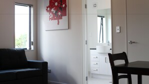 Ein modernes Zimmer mit einer Couch, einem Esstisch mit Stühlen, einem weißen Schrank und einer Tür zu einem weiteren Raum.