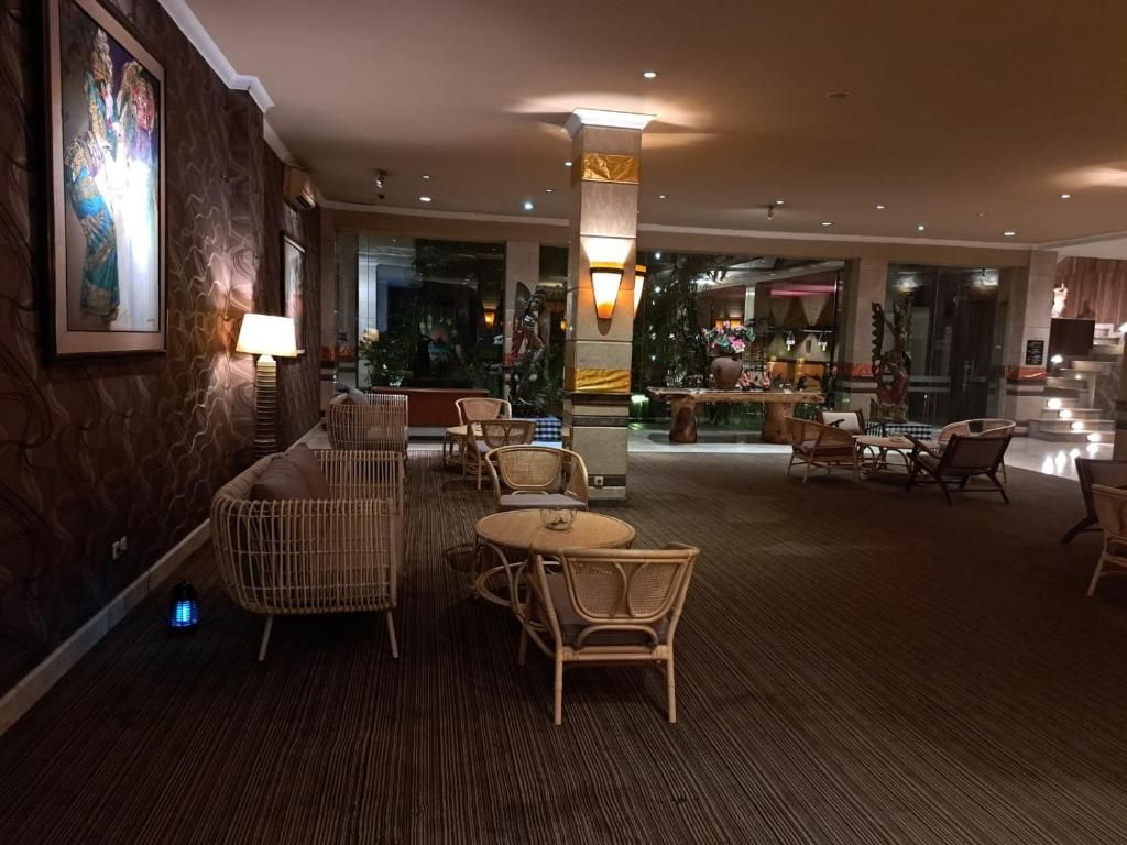 A hotel lobby with a seating area, a reception desk, and a large window.