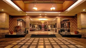 A spacious lobby with a checkered floor, large chandeliers, and decorative statues. - Bali World Hotel (Bandung)
