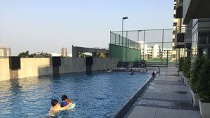 An outdoor swimming pool with a clear view of the surrounding buildings and a paved walkway. - The Lake 3 Condominium (Pak Kret)