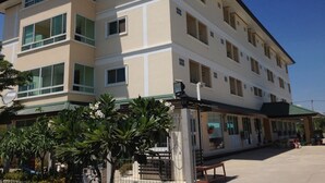 Un edificio de varios pisos con techo plano, ventanas amplias y un espacio exterior cubierto con asientos.
