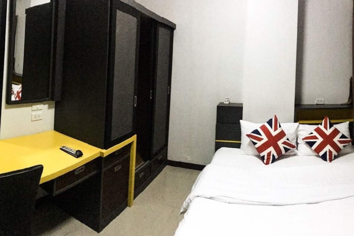 A hotel room with a bed, a desk, a chair, a wardrobe, and a window with curtains.
