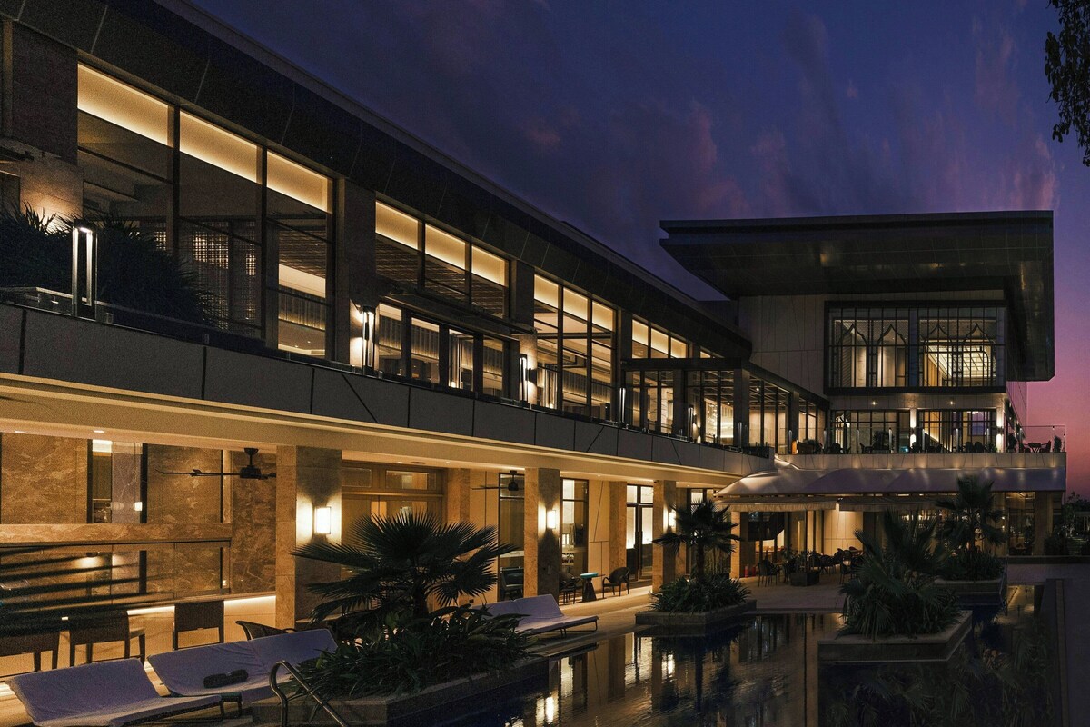 Un hôtel moderne doté d’une piscine, d’un espace extérieur aménagé et d’une façade bien éclairée.