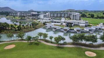 A modern resort with multiple buildings, a central water feature, and surrounding greenery.