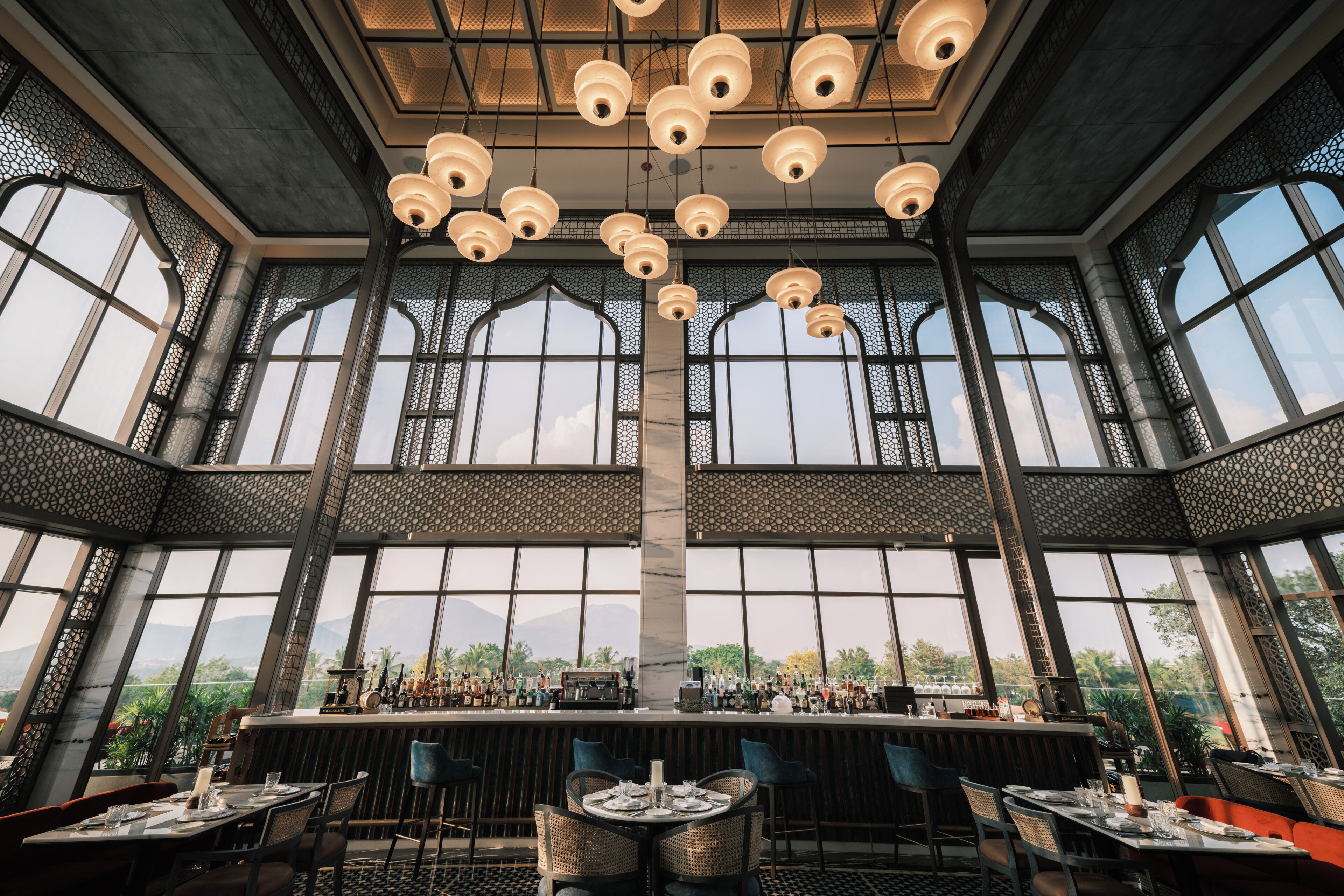 Un amplio bar con techos altos y grandes ventanales, con vistas al exterior.