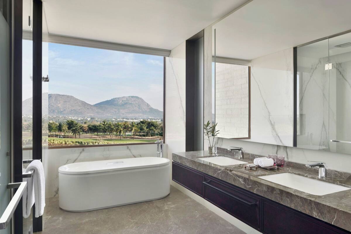 Un baño moderno con una bañera grande, dos lavamanos y un espejo amplio.