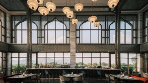 Un grand espace bar doté de hauts plafonds, de grandes fenêtres et de luminaires suspendus.