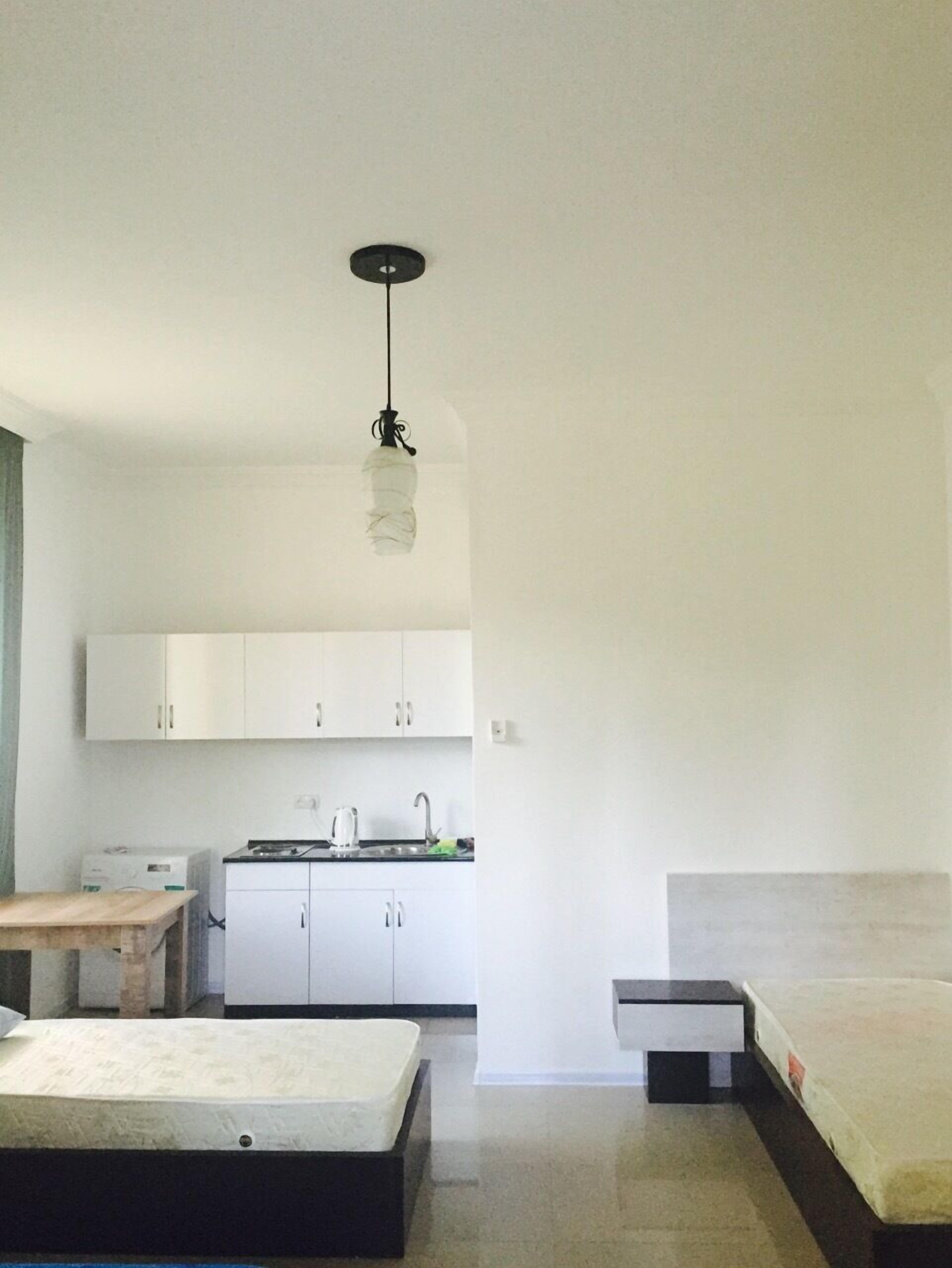 A modern, minimalist bedroom with a large bed, a small bedside table, and a built-in bench.