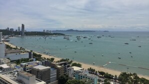 A coastal cityscape with a beach, numerous boats, and high-rise buildings in the background. - Viewtalay6 by Pat 42 (Pattaya)