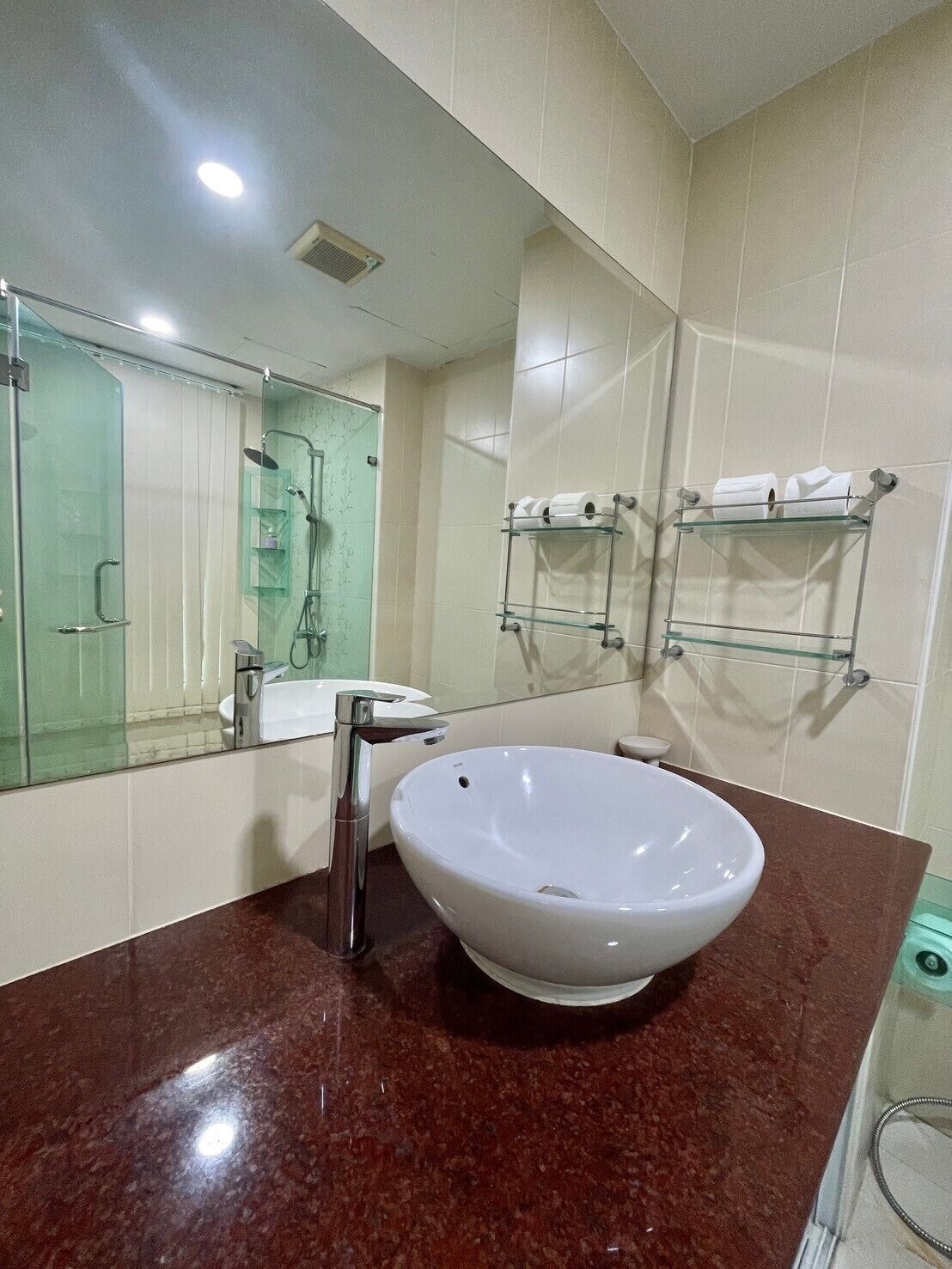 A bathroom with a white sink, a glass shower enclosure, and two towel racks on the wall.