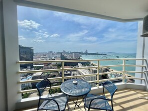 A balcony with a table and chairs, overlooking a cityscape and the sea. - Viewtalay6 by Pat 42 (Pattaya)