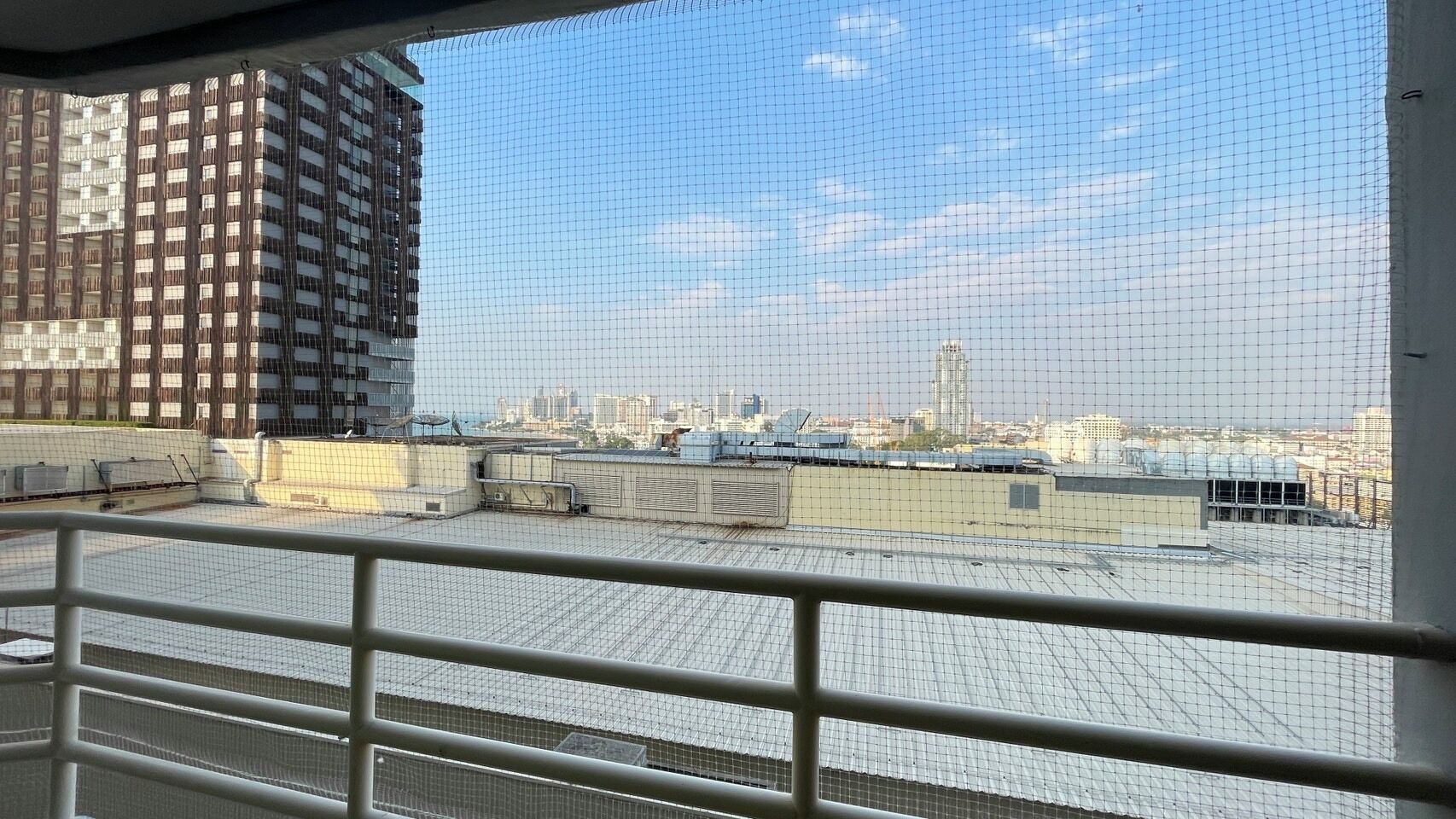 Vista desde la azotea con barandilla de metal, cielo despejado y edificios a lo lejos.