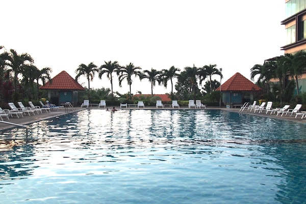 Een buitenzwembad, ligstoelen bij het zwembad