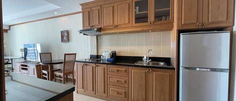 A kitchen with wooden cabinets, a stainless steel refrigerator, and a dining area with a table and chairs.